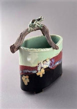 Load image into Gallery viewer, hand sculpted frog sits on a branch arching over an oval vase in celdon, brown-black tenmoku and red glazes.
