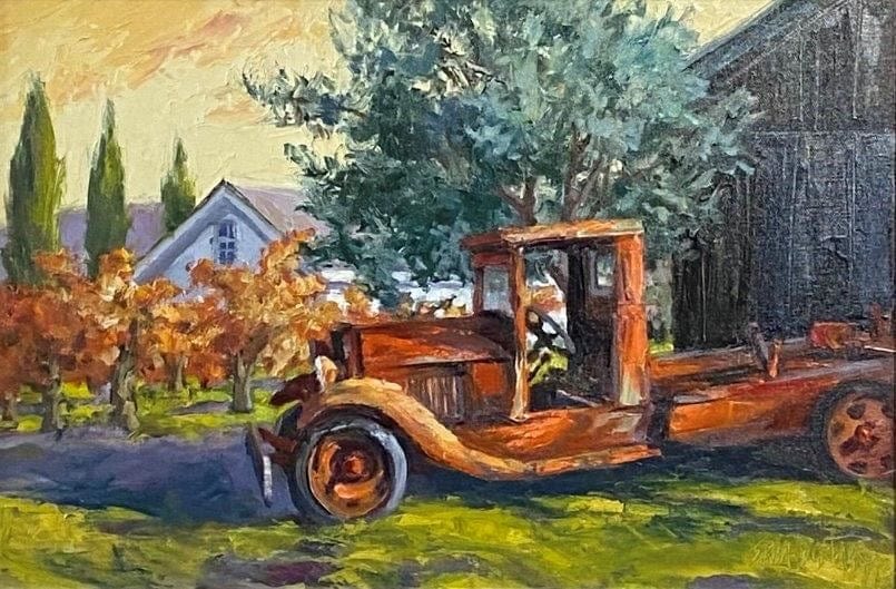 Ancient truck sits in shabby splendor near a barn, its color reflected in the fall vineyards 
