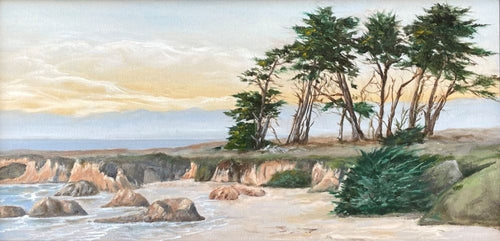 An old grove of cypress trees sit atop the green gray grass of the Pudding Creek headlands overlooking the beach. Yellow late afternoon clouds hang over the sea.