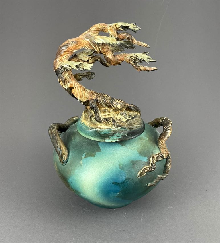 cypress sculpture on a covered jar, wood tones, teal and green jar