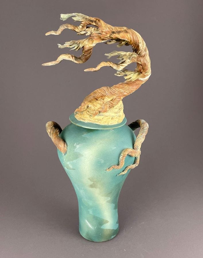 Tall ginger jar with lid. Cypress tree tops the lid with tree branch handles on a soft teal and green jar.