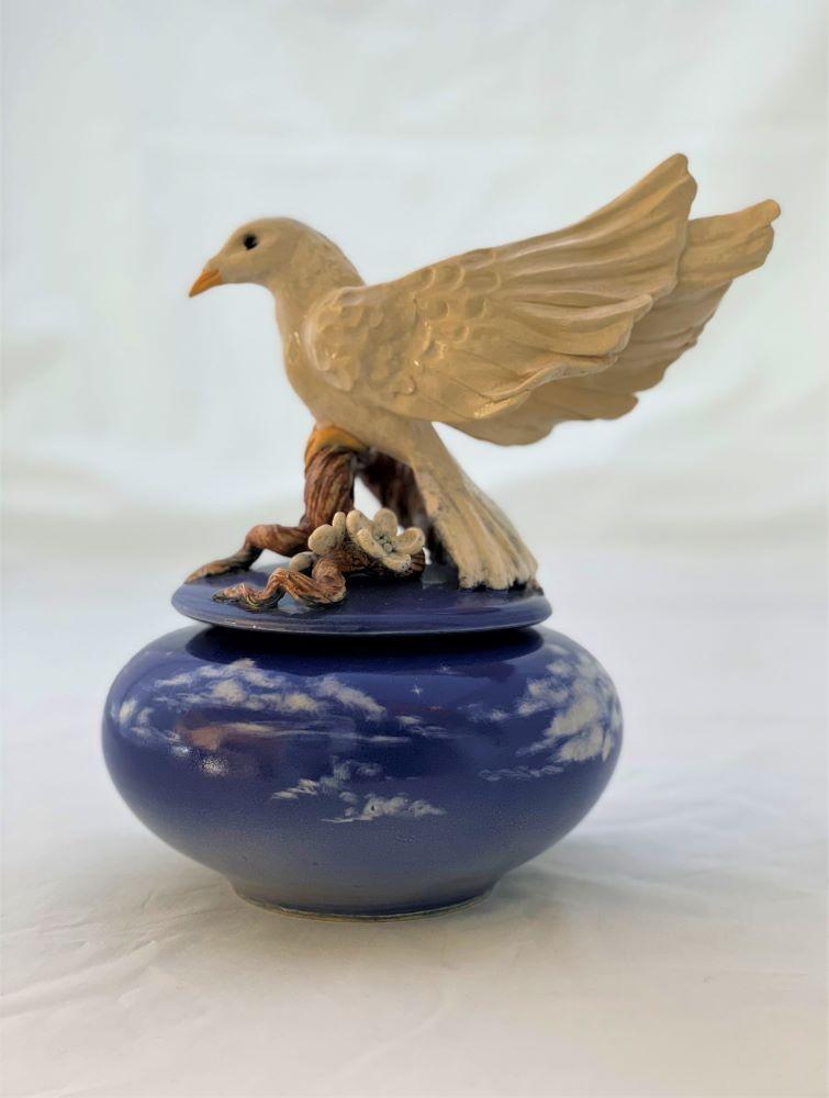 White dove atop a blossoming branch on a twilight blue jar  with clouds