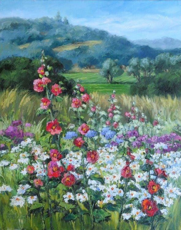 A profusion of blooms, pink-red hollyhocks, white and yellow daisies, with touches of blue and purple, and looking back to green fields and gentle hills.