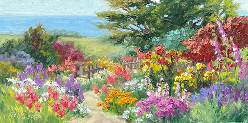 The view from a lush flowering garden looking over the meadow the the sea.