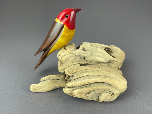 Western Tanager bird sculpture, red head, yellow breast, brown back perched on driftwood base
