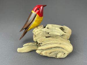 Western Tanager bird sculpture, red head, yellow breast, brown back perched on driftwood base