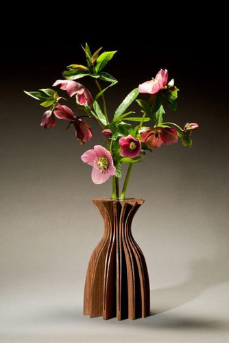 Jasmine vase of walnut, one piece of wood cut and opened to create a graceful form. With glass tube for water and flowers.