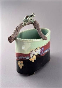 hand sculpted frog sits on a branch arching over an oval vase in celdon, brown-black tenmoku and red glazes.